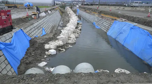 ブルーシートで養生した水路の改修工事