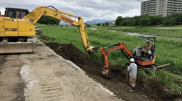 河川の法面で作業する2台のバックホウ