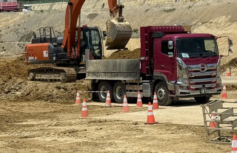 造成現場でダンプカーへ土砂を積み込むバックホウ