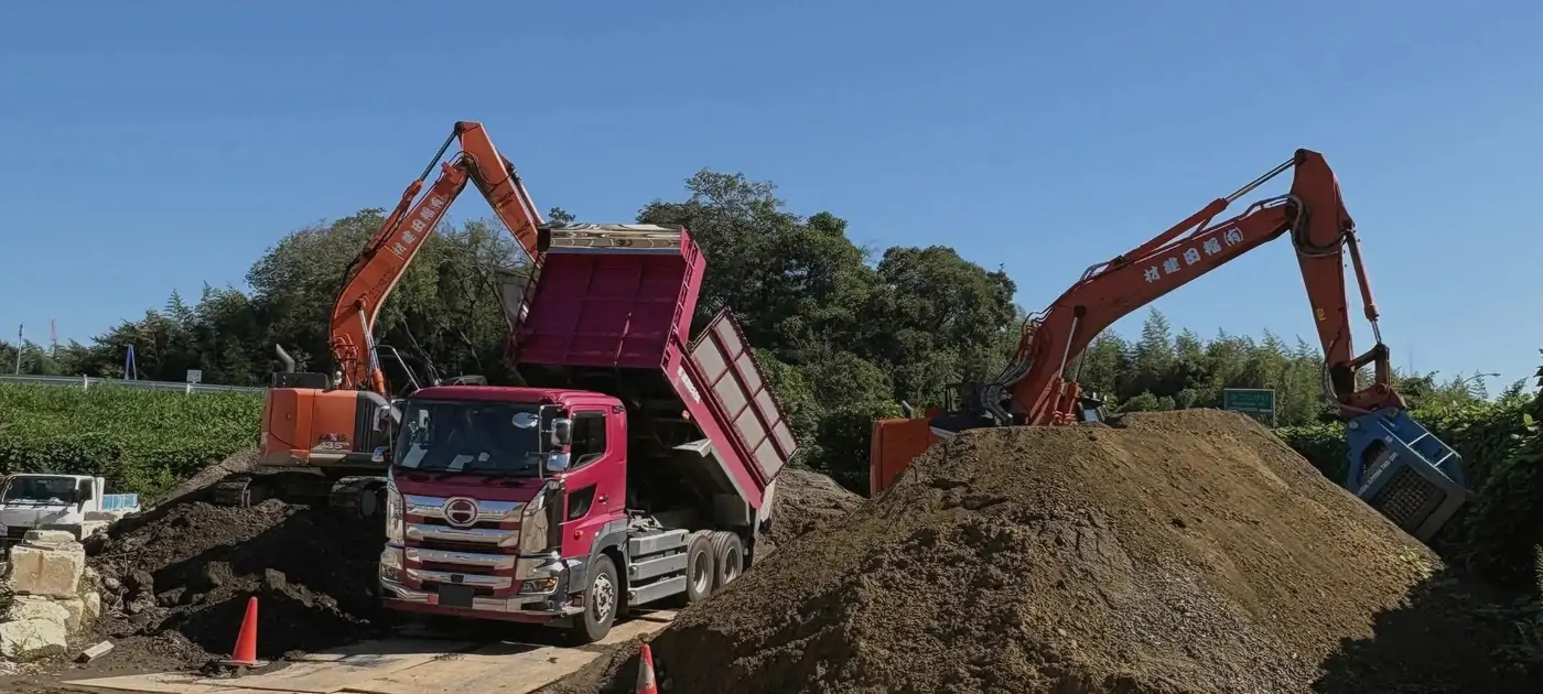 ダンプカーとバックホウが並ぶ有限会社福田建材の資材置場